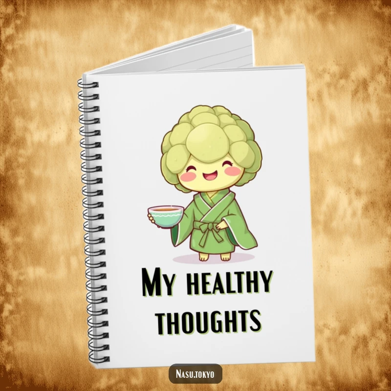 Funny broccoli in a green kimono presenting a teacup, a stylish and funny notebook for jotting down notes.
